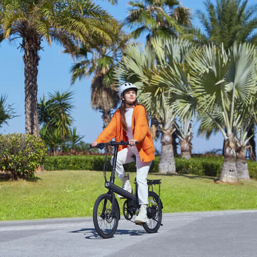 Woman riding Xiaomi QiCycle C2 electric bike on a sunny day surrounded by palm trees