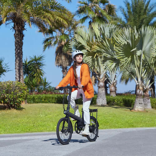 Person riding the Xiaomi QiCycle C2 electric bike on a sunny day in a park.